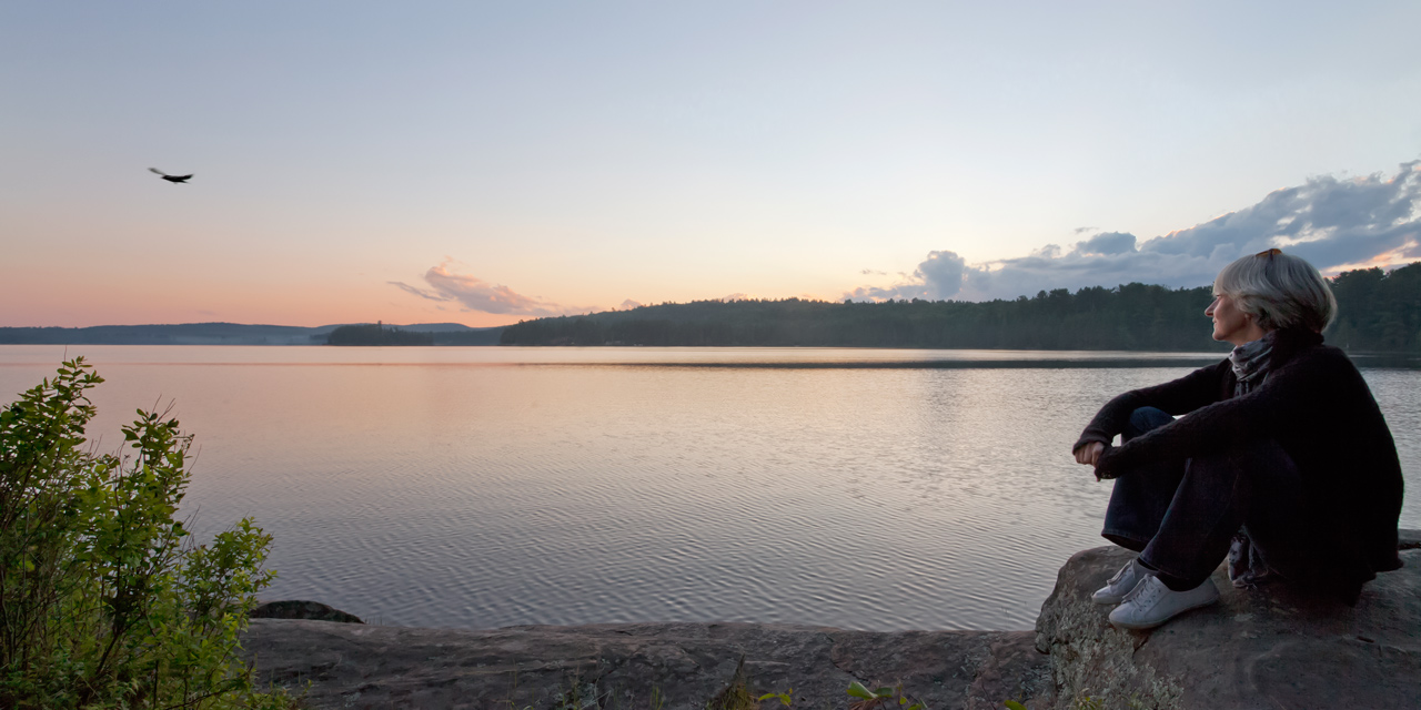 woman and crow watching algonquin park sunset in summer